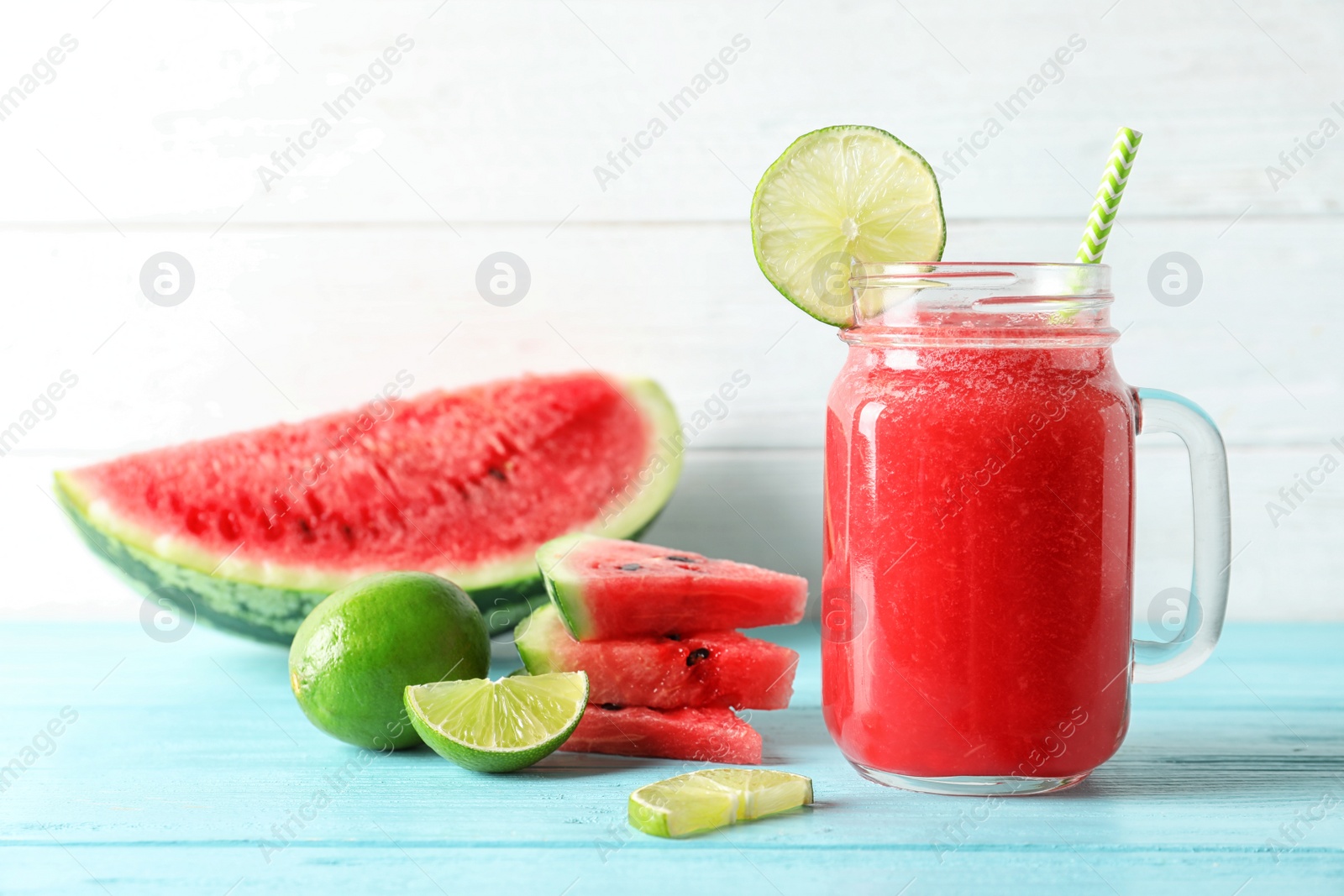 Photo of Tasty summer watermelon drink in mason jar and sliced fruits on table