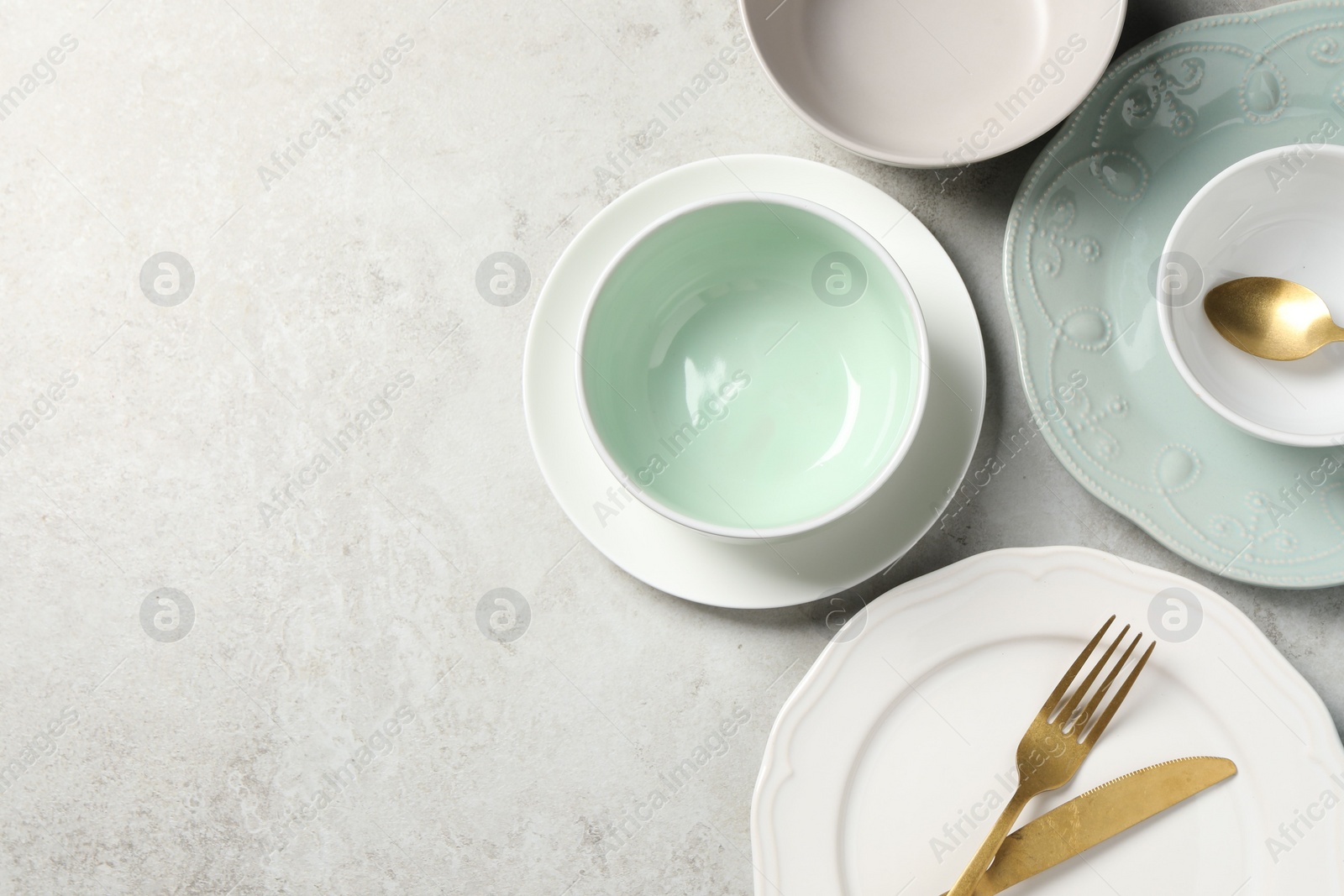 Photo of Beautiful ceramic dishware and cutlery on light grey table, flat lay. Space for text