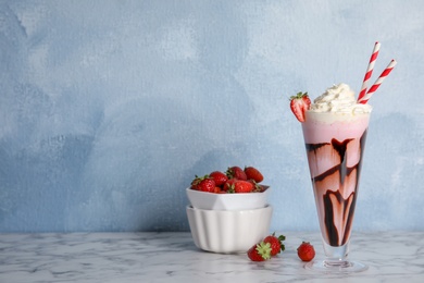 Photo of Glass of delicious milk shake and bowl with strawberries on table. Space for text