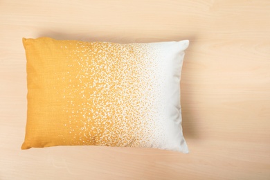 Soft decorative pillow on wooden background, top view