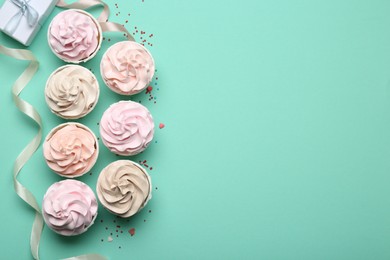 Photo of Delicious birthday cupcakes, ribbon and sprinkles on turquoise background, flat lay. Space for text