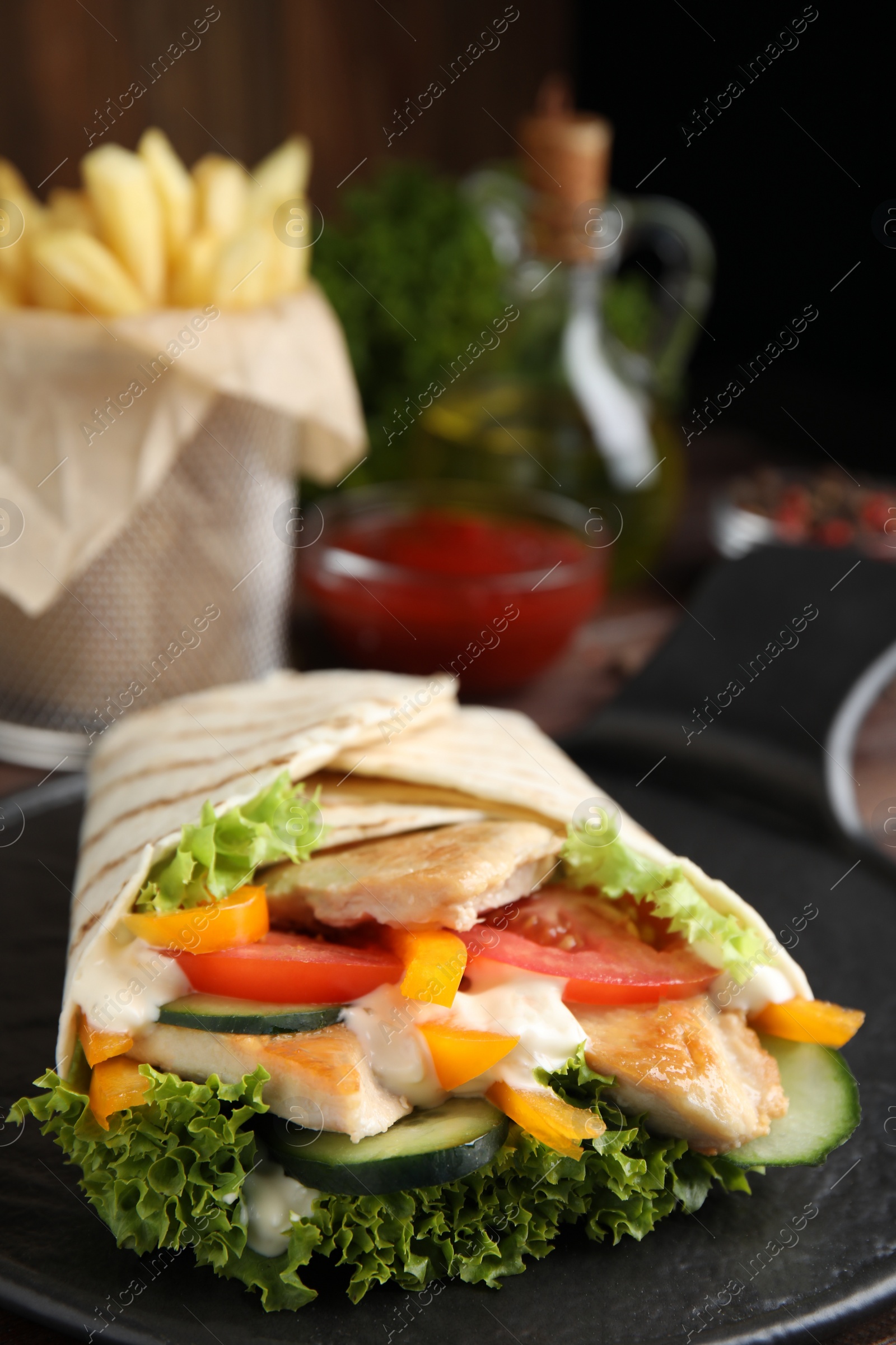 Photo of Delicious shawarma with chicken meat and vegetables  on slate plate, closeup