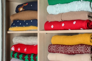 Photo of Folded winter clothes on shelves in wardrobe