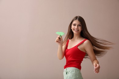 Photo of Beautiful teenage girl with paper plane on beige background. Space for text