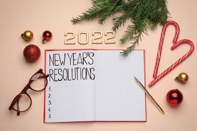 Photo of Making New Year's resolutions. Flat lay composition with notebook, 2022 numbers and festive decor on beige background