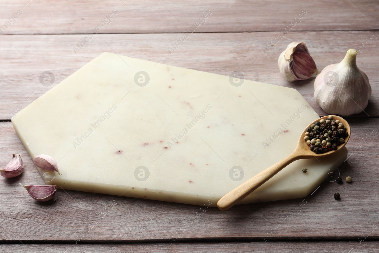 Photo of Cutting board, pepper and garlic on light wooden table. Space for text