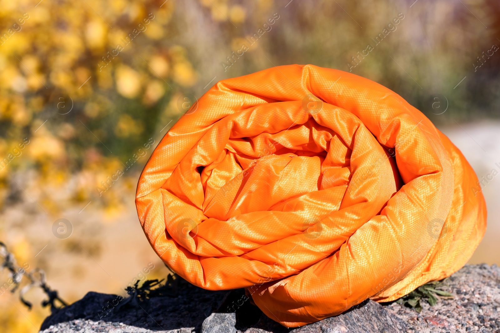 Photo of Orange sleeping bag on blurred background. Camping equipment