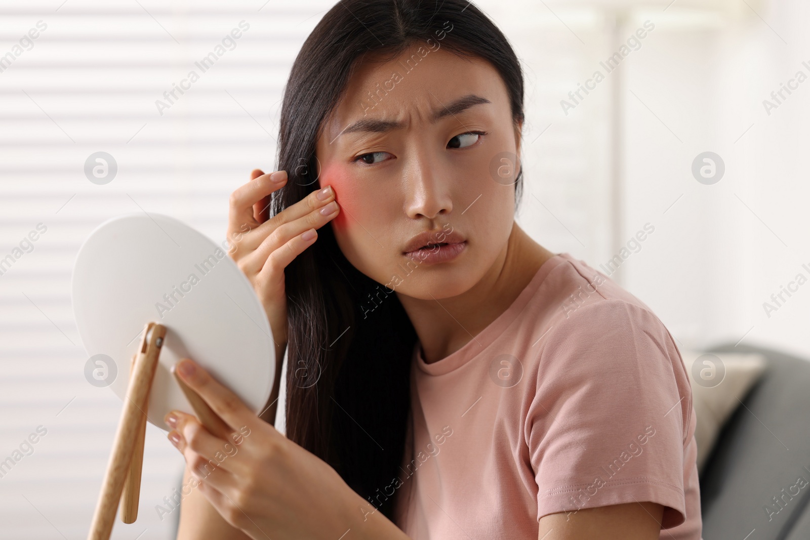 Photo of Suffering from allergy. Young woman with mirror checking her face in living room