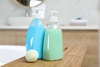 Bottles of shower gels and bath bomb on wooden table indoors