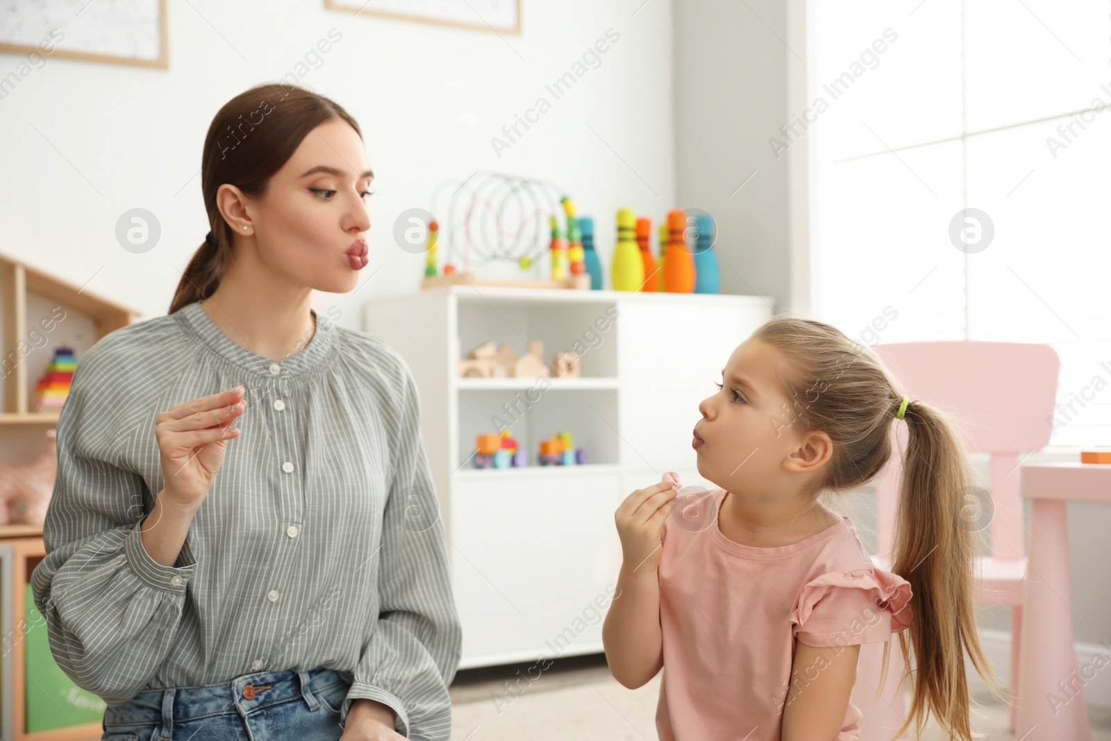 Photo of Speech therapist working with little girl in office