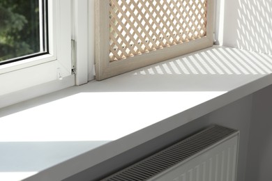 Photo of Empty white window sill and decorative wooden shutter indoors