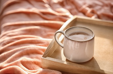 Tray with cup of hot coffee on soft plaid