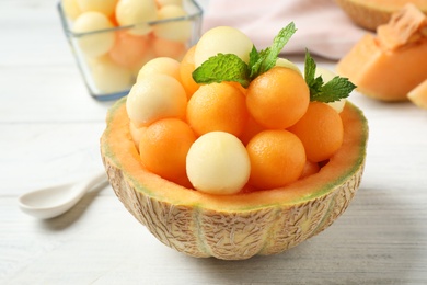 Photo of Different melon balls with mint on white wooden table