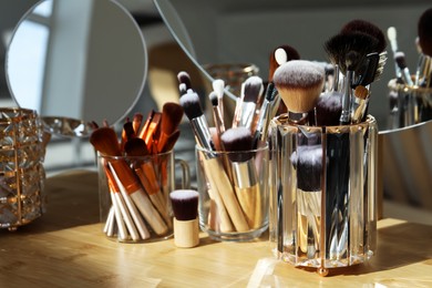 Photo of Set of professional brushes and mirror on wooden table