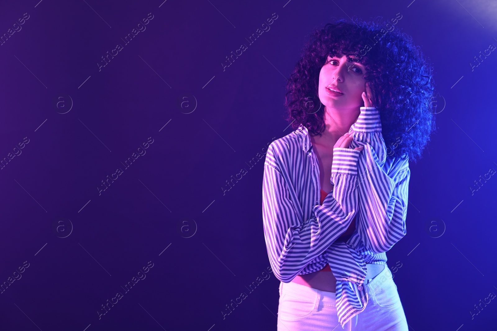 Photo of Beautiful young woman posing on color background in neon lights. Space for text