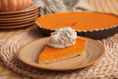 Piece of fresh homemade pumpkin pie with whipped cream on table