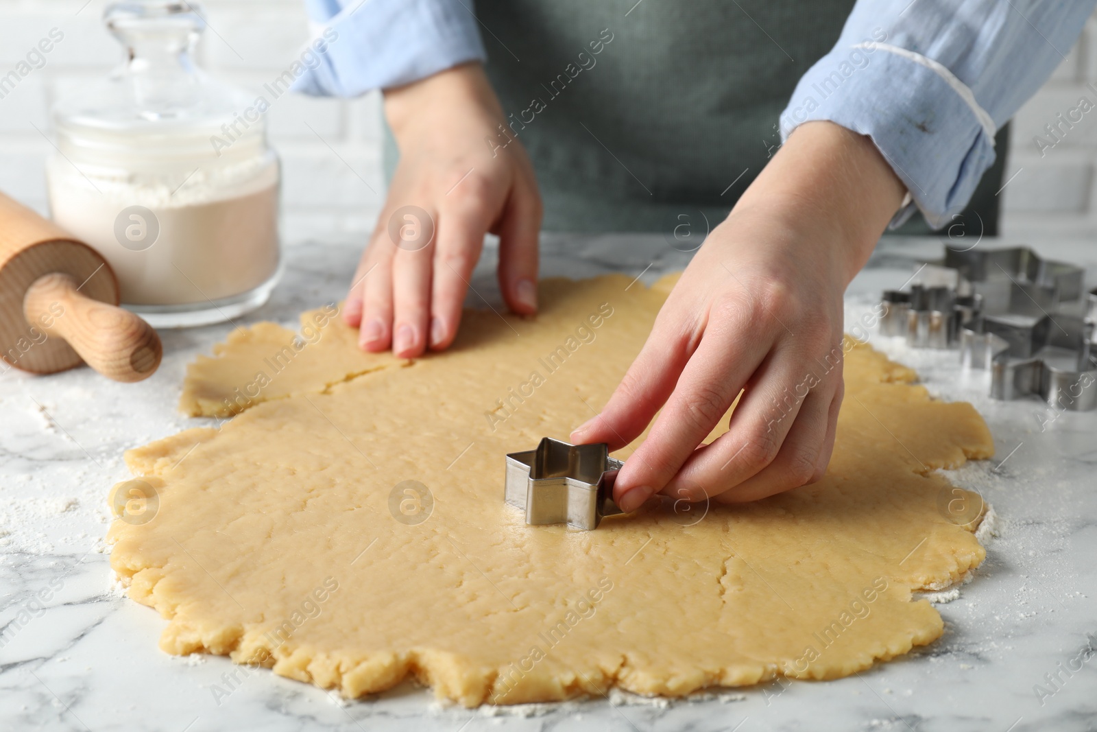 Photo of Shortcrust pastry. Woman making cookies with cutter at white marble table, closeup