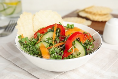 Photo of Delicious vegetable salad with microgreen served on white table