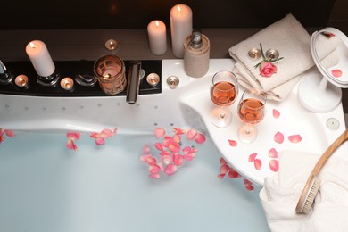 Photo of Bathtub with glasses of wine and candles indoors, above view. Romantic atmosphere