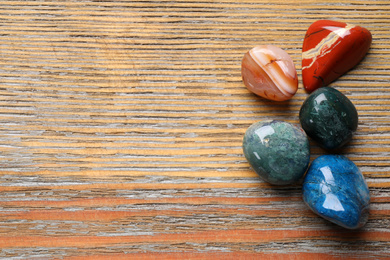 Photo of Beautiful gemstones on wooden table, top view with space for text. Healing crystals