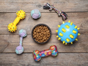 Flat lay composition with different pet toys and feeding bowl on wooden background