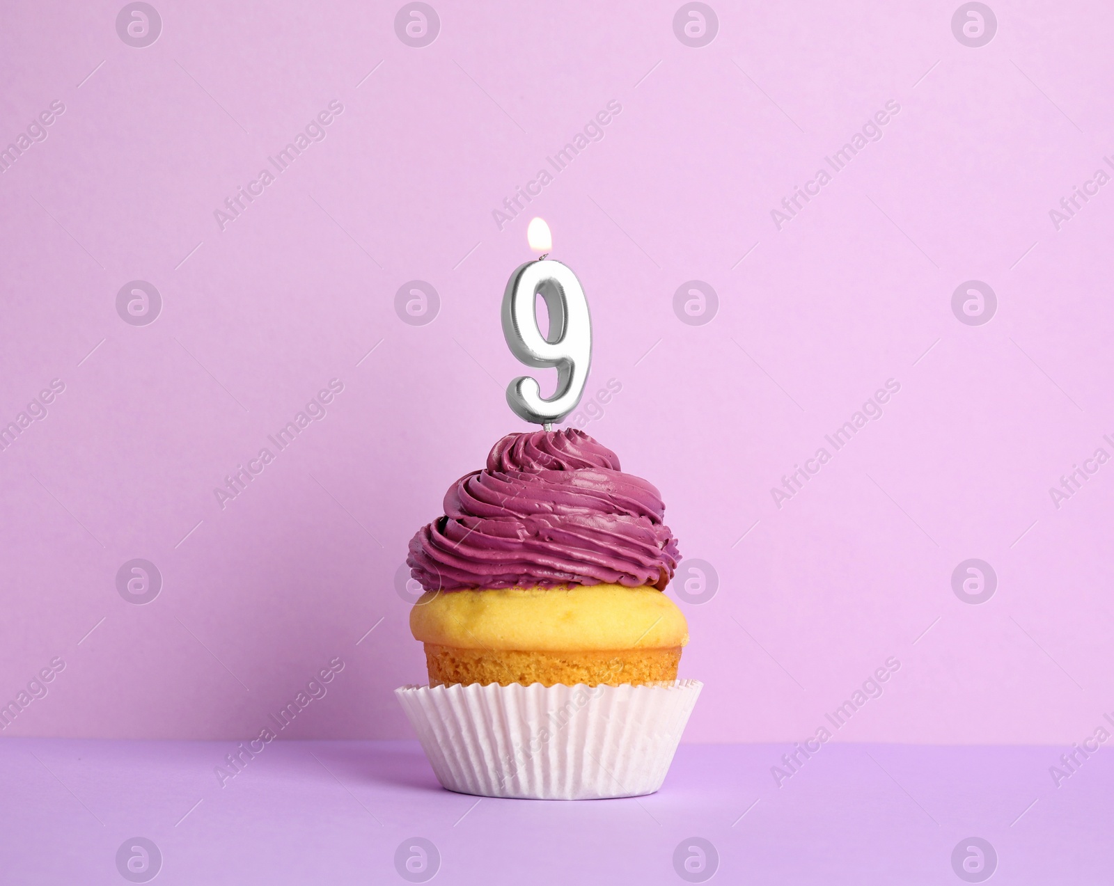 Photo of Birthday cupcake with number nine candle on violet background
