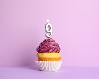 Birthday cupcake with number nine candle on violet background
