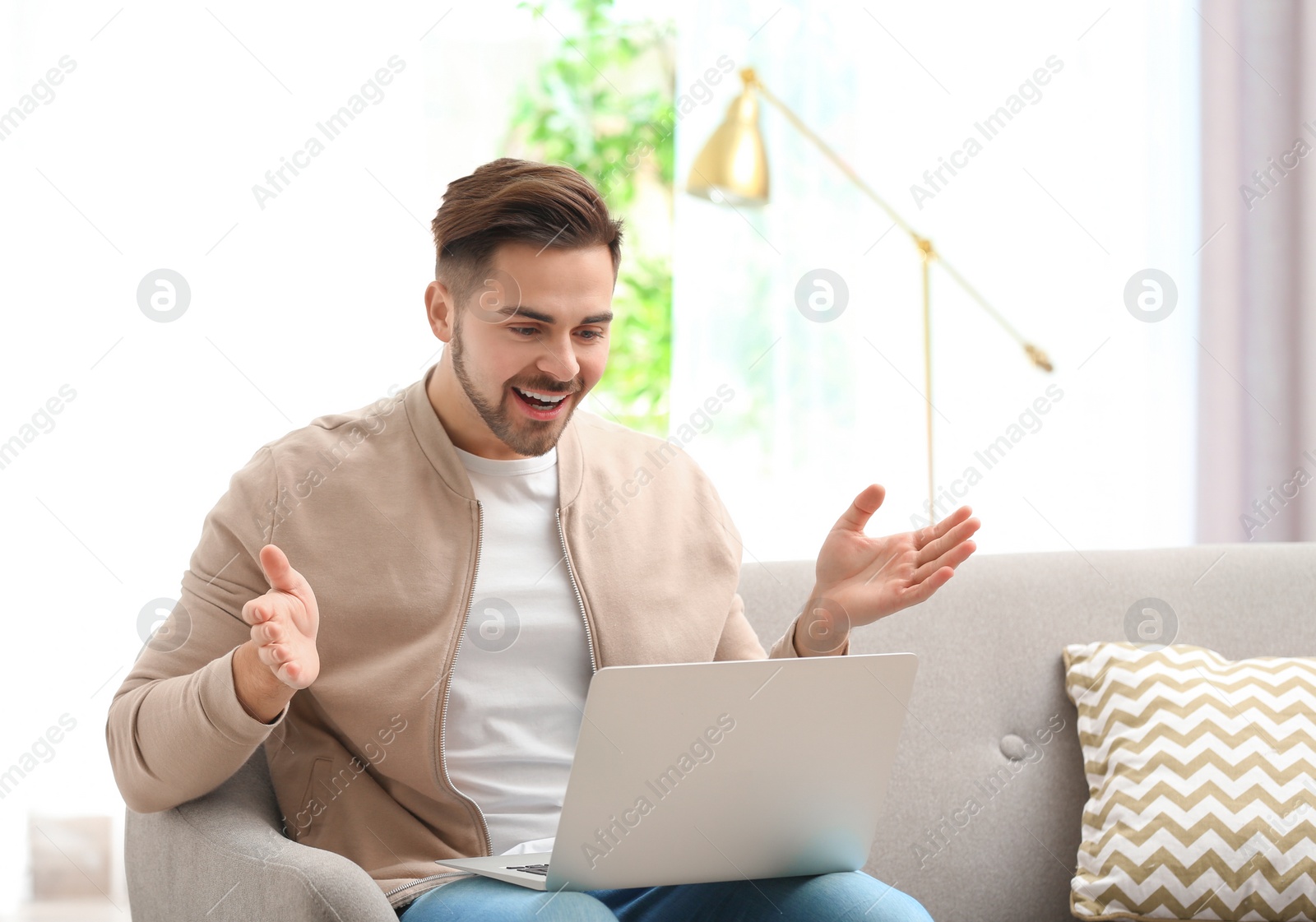 Photo of Man using laptop for video chat in living room