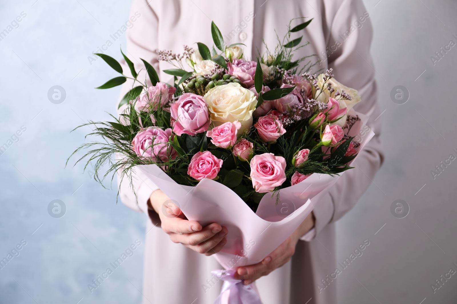 Photo of Woman with bouquet of beautiful roses on light blue background, closeup