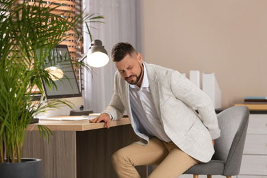 Man suffering from hemorrhoid at workplace in office