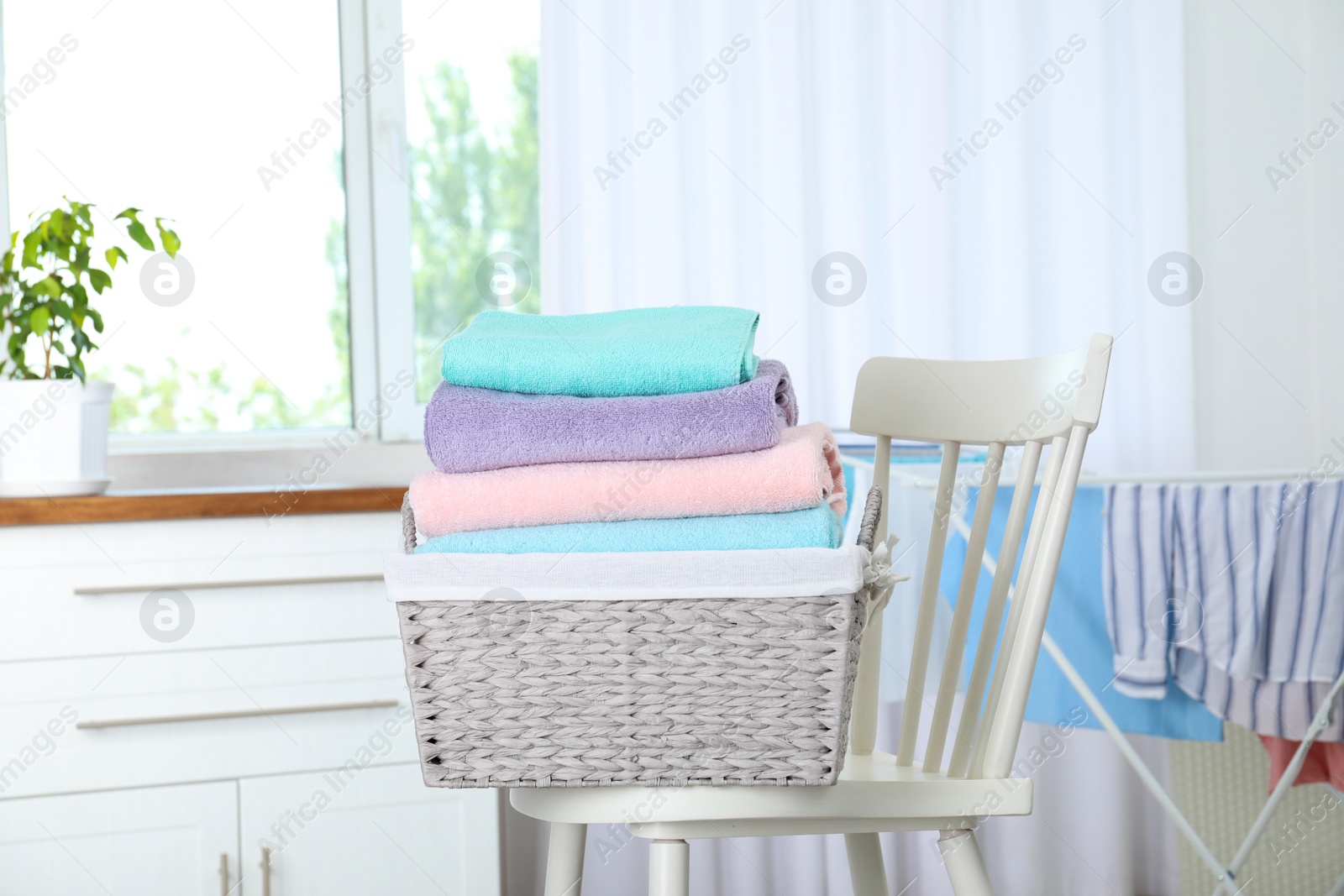 Photo of Basket with clean laundry on chair at home