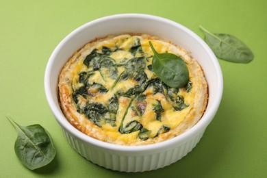 Photo of Delicious pie with spinach on green background, closeup