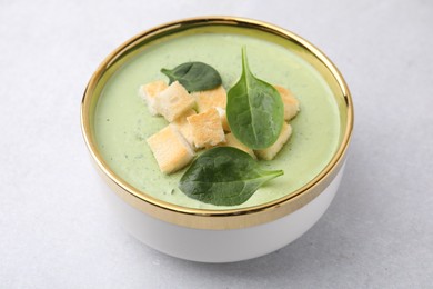 Delicious spinach cream soup with croutons in bowl on light grey table