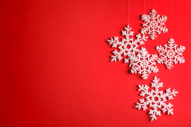 Photo of Beautiful decorative snowflakes hanging on red background, space for text