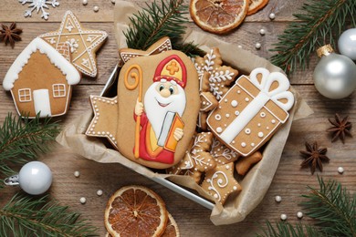 Photo of Tasty gingerbread cookies and festive decor on wooden table, flat lay. St. Nicholas Day celebration
