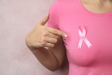 Photo of Woman with pink ribbon on color background, closeup. Breast cancer awareness