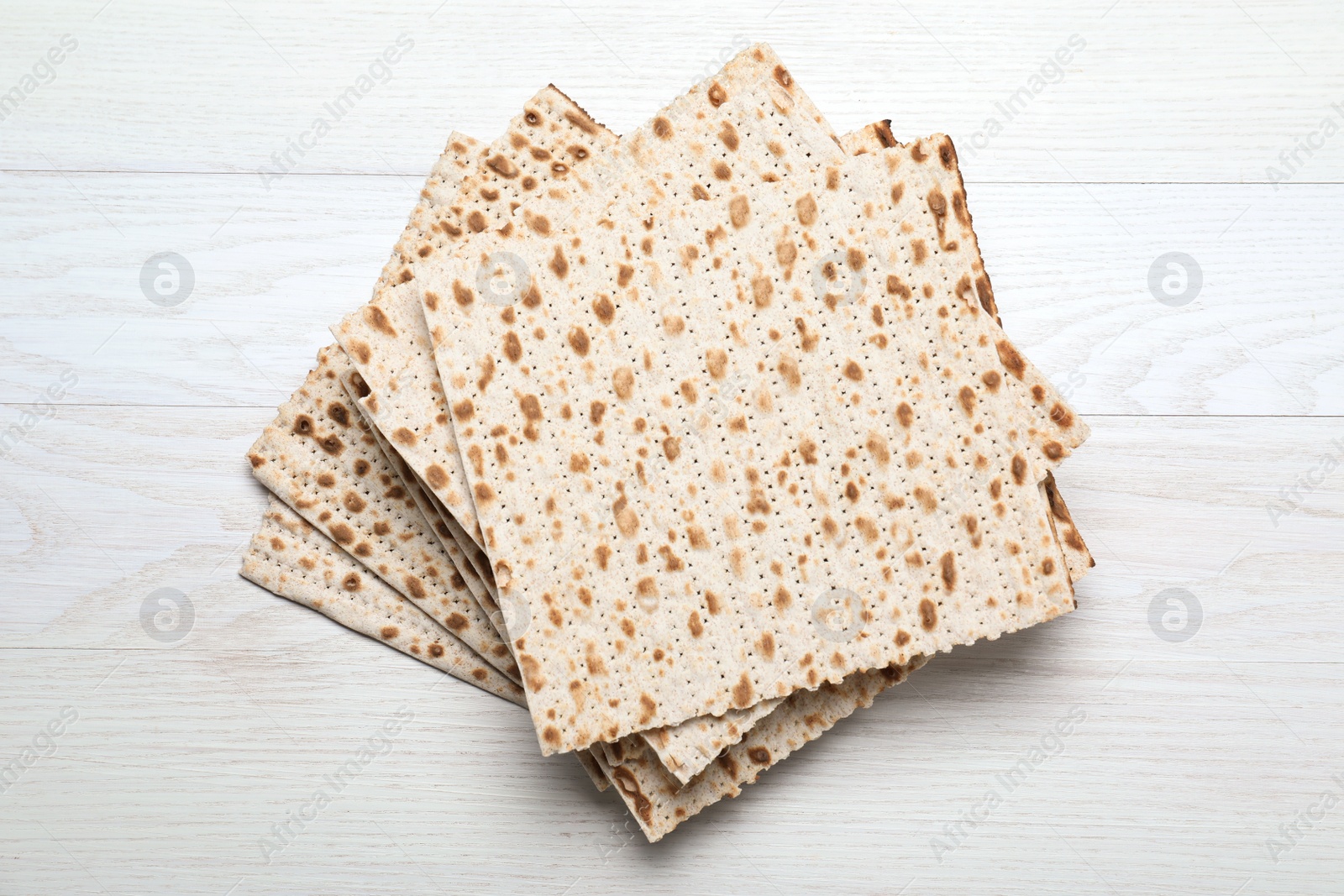 Photo of Stack of matzos on white wooden table, top view