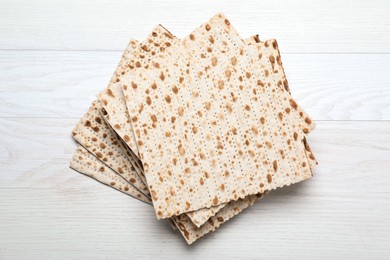 Photo of Stack of matzos on white wooden table, top view