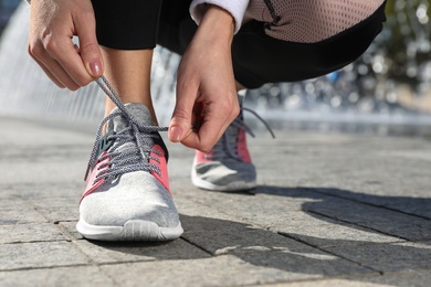 Photo of Sporty woman tying shoelaces before running outdoors