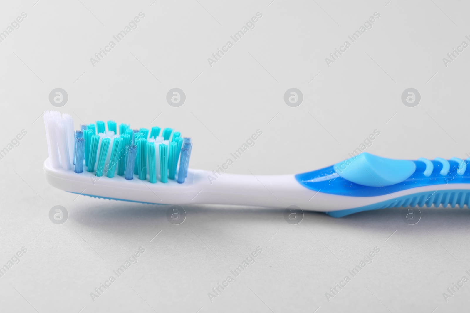 Photo of One plastic toothbrush on light background, closeup