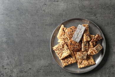 Photo of Plate with cookies and cereal bars on grey background, top view. Whole grain snack