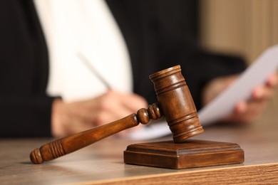 Judge working with document indoors, selective focus. Mallet on wooden table, closeup