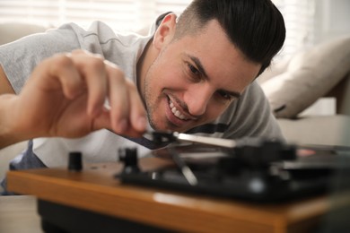 Photo of Happy man using turntable at home, closeup