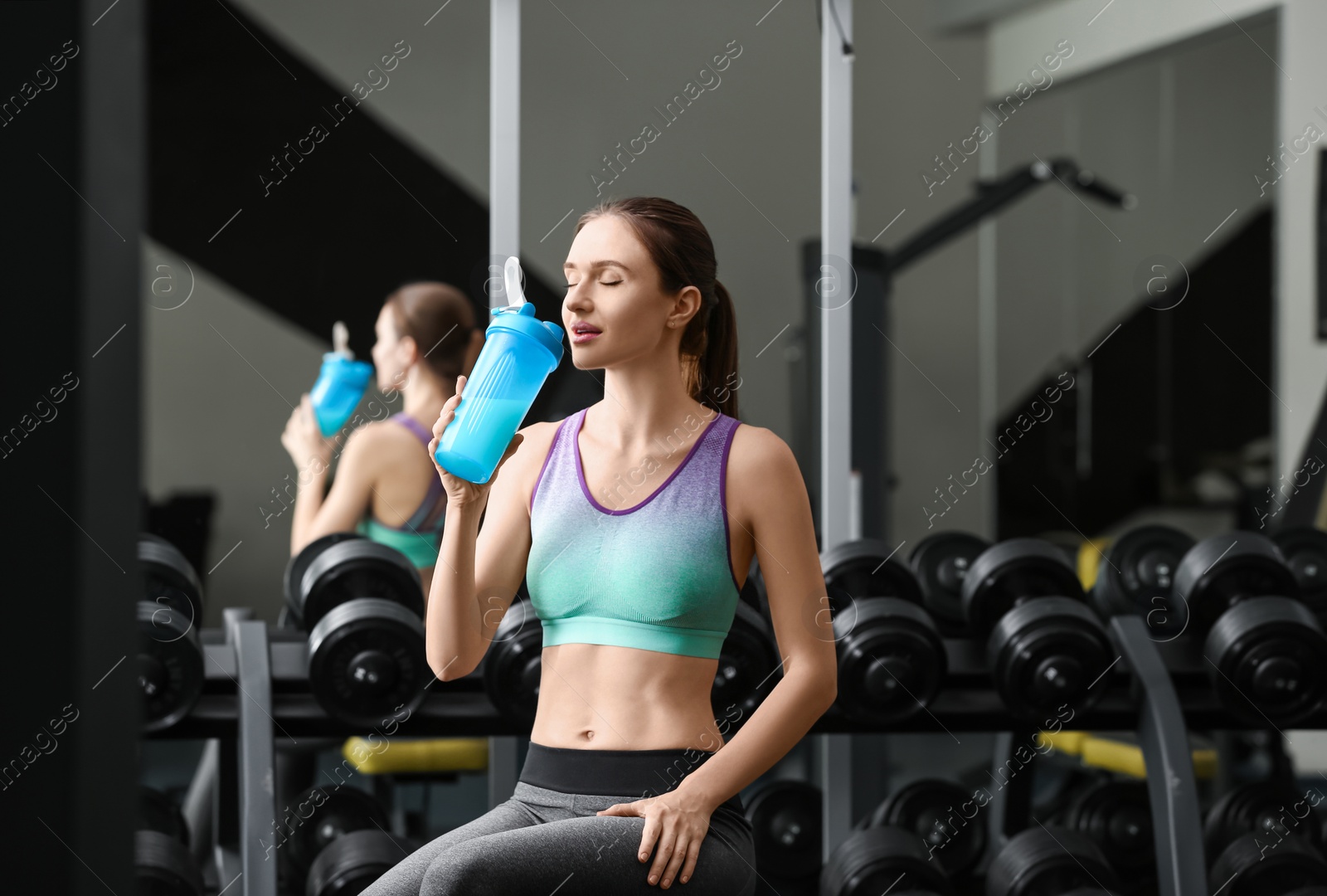 Photo of Athletic young woman drinking protein shake in gym