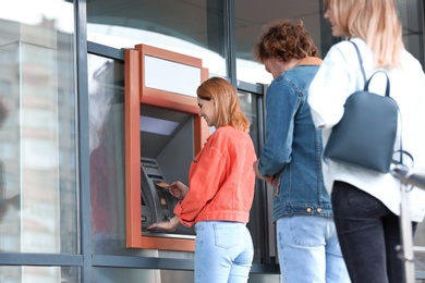 Photo of People standing in queue to cash machine outdoors