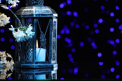 Photo of Arabic lantern and flowers on mirror surface against blurred lights at night. Space for text
