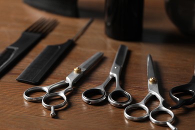 Hairdresser tools. Different scissors and combs on wooden table, closeup