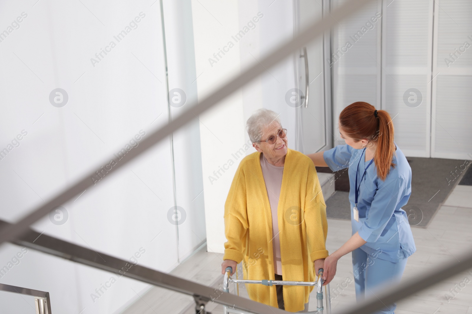 Photo of Nurse assisting senior woman with walker in hospital