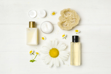 Photo of Flat lay composition with chamomiles and cosmetic products on white wooden table