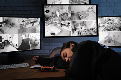 Photo of Female security guard sleeping near monitors at workplace